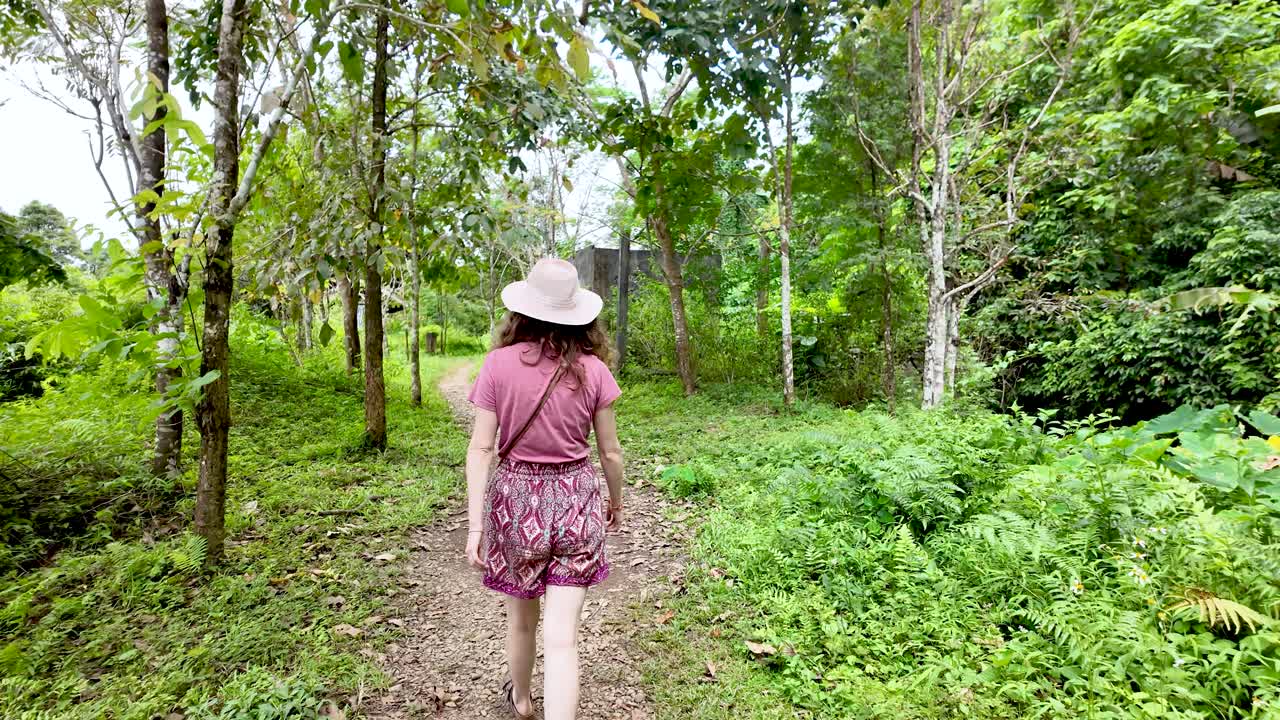 Female tourist is walking through a lush green forest near Vang Vieng Laos exploring Blue Lagoon 3 on a vacation trip