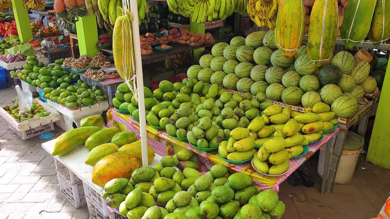 una variedad de frutas y verduras frescas tropicales y exóticas, incluidos mangos, papaya y melón de agua en un puesto de mercado en la capital dili, timor leste, sudeste de asia