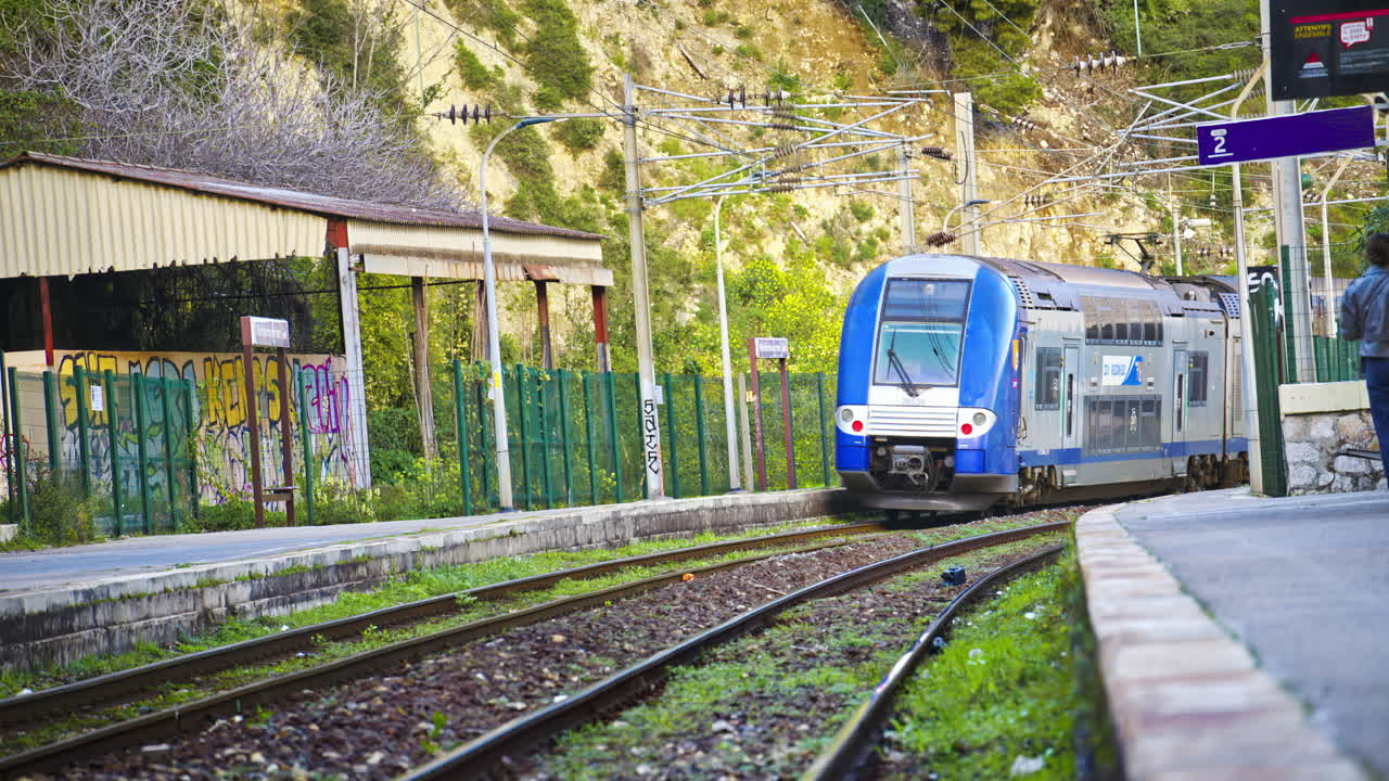 Blue train moving on the rails near a station