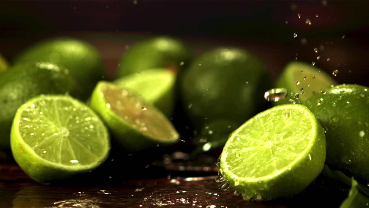 Refreshing Water Splashes on Vibrant Green Limes and Slices