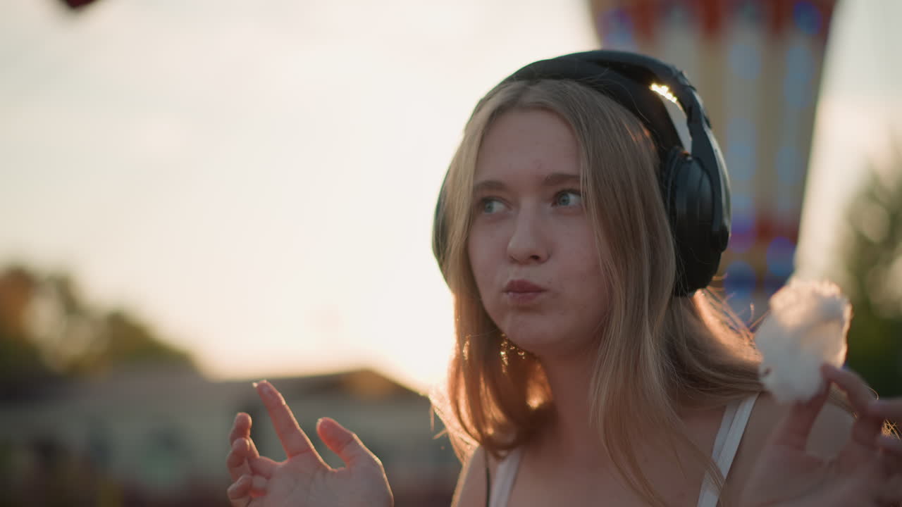 Una donna si gusta una dolce prelibatezza, una ragazza assapora gioiosamente una delizia zuccherina, una signora trova la felicità in una nuvola di zucchero filato, una donna prova beatitudine mentre si concede una stravaganza di zucchero filato