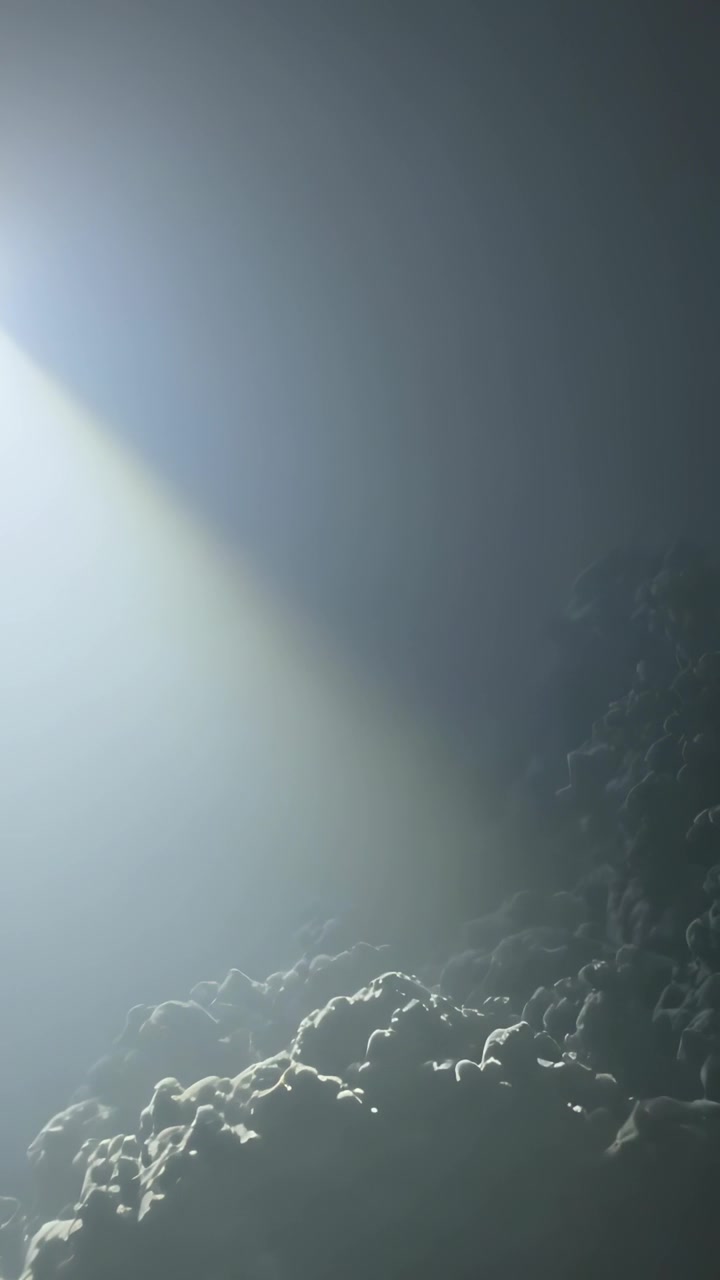 Vídeo vertical: Feixe de torre giratório iluminando a costa rochosa, guiando navios, com luz de navegação vermelha e espaço para texto.