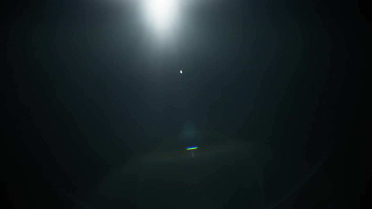 Blue lens flare fading out to black background. Slow motion