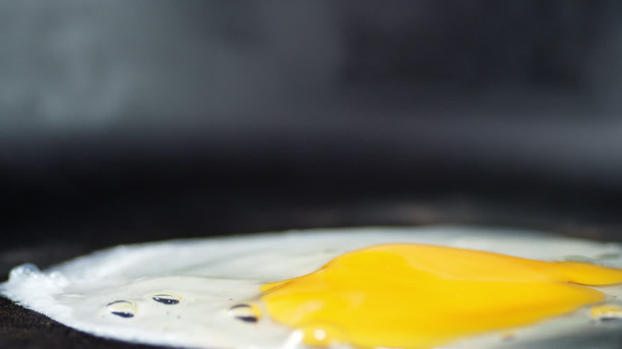 A fresh egg falls on a hot frying pan.