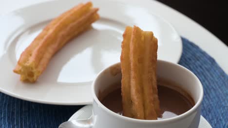 masa frita de bocadillo español conocida como churros sumergida en salsa de chocolate caliente