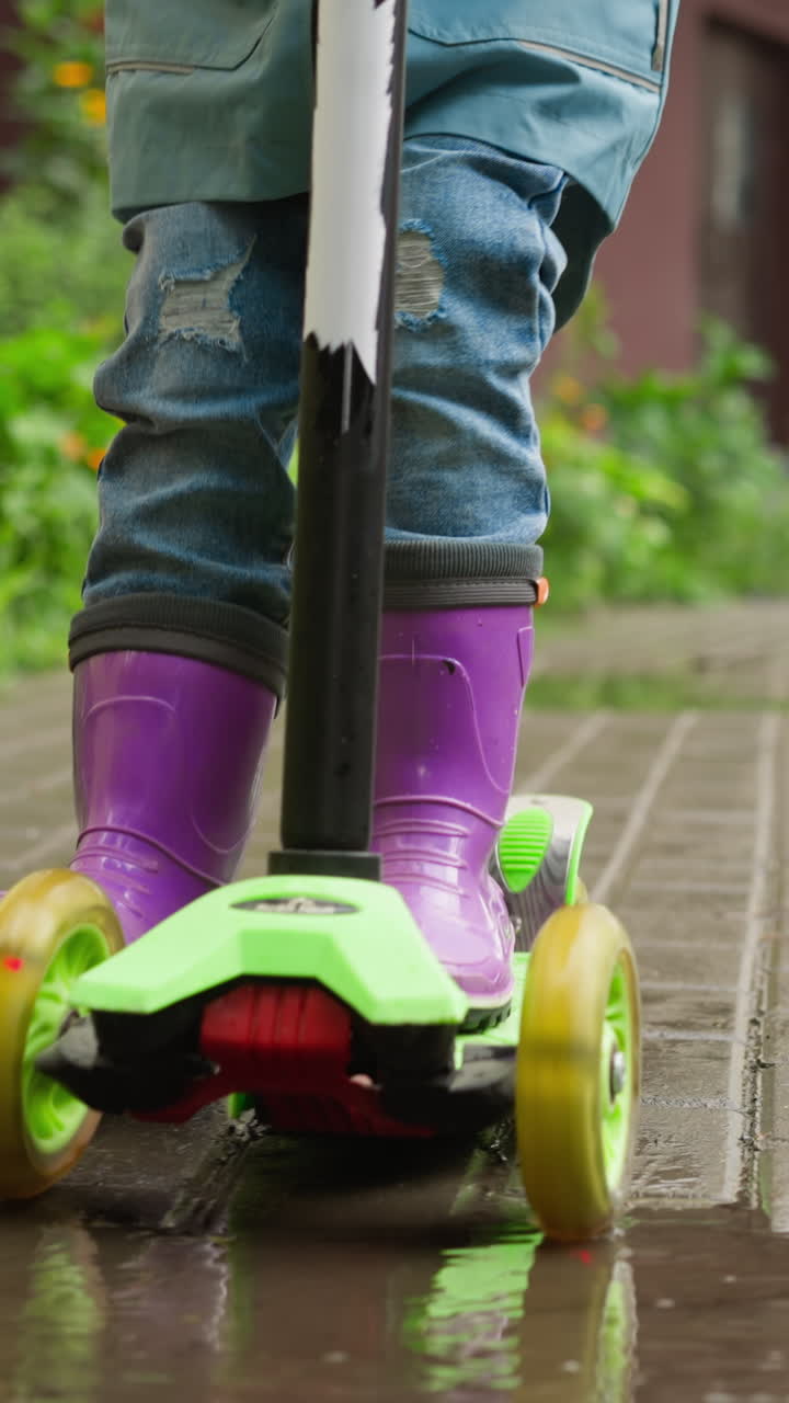 Kid scoots along rain-slicked pavements. Spirited child happily navigates three-wheeled scooter reveling in simple pleasures of childhood among drizzle