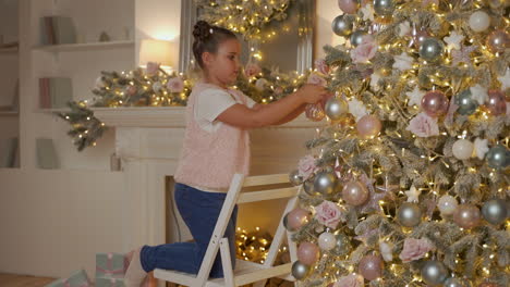 little girl decorates christmas tree with balls and ornaments