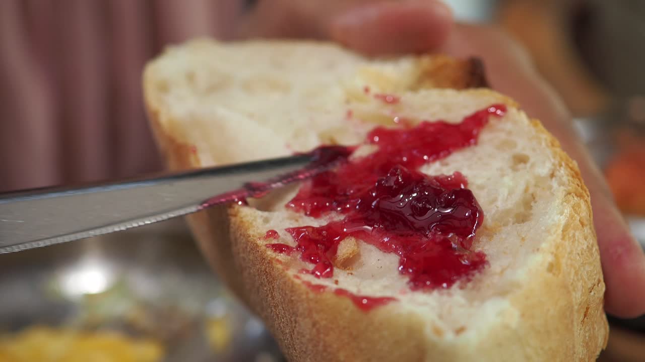 la mano esparciendo mermelada en una rebanada de pan