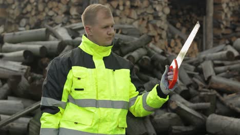 lumberjack. man woodcutter with small saw. choosing electric chainsaw. sawn logs, firewood, sawmill