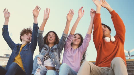 um grupo de amigos adolescentes de duas meninas e dois meninos levantam as mãos e dançam ao compasso 1