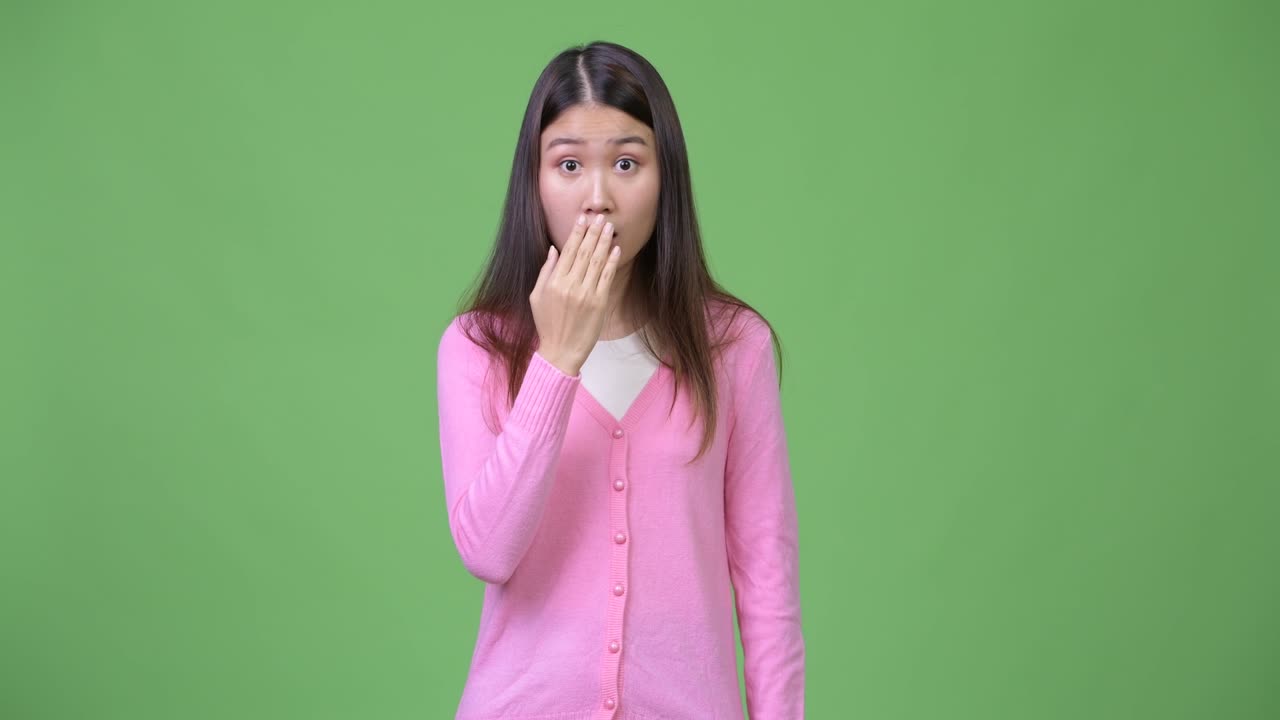 Young beautiful Asian woman looking shocked