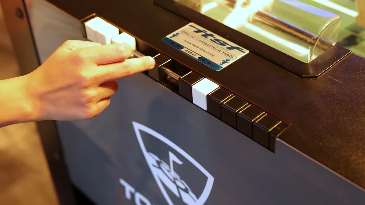 Hand adjusting foosball score counter on table