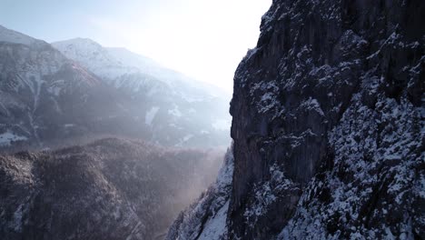 Close-aerial-view-of-rocky-mountains-with-trees-covered-in-snow-during-a-sunny-winter-day