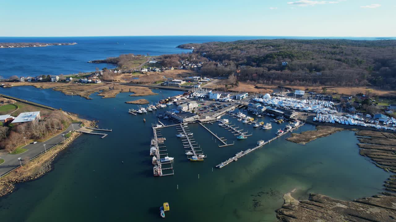 Flygande omloppsbild över Cape Ann Marina med förtöjda båtar och blått hav, Gloucester, Massachusetts, USA