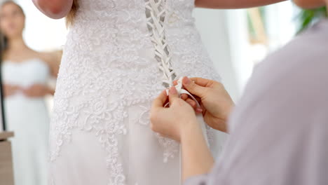 friends helping woman with wedding dress knot