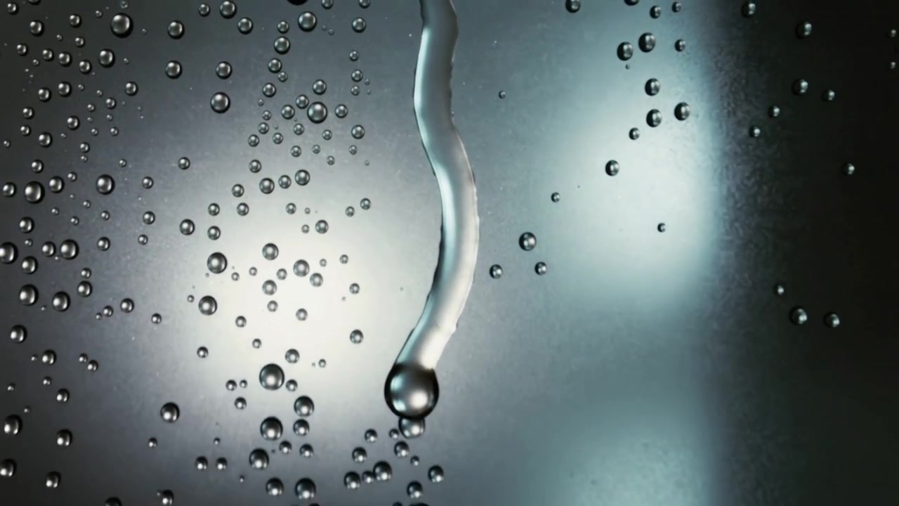 Sliding elongated condensed droplet forming thread with bead down glass pane, pulled by gravity