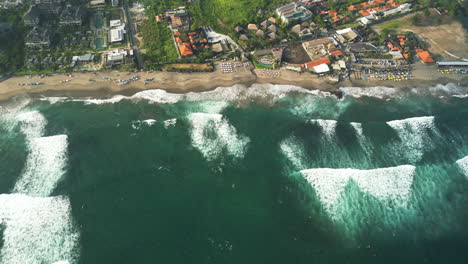 aerial birds eye shot of waves of ocean reaching batu bolong beach with surfer spot on bali - air pollution and climate change on island