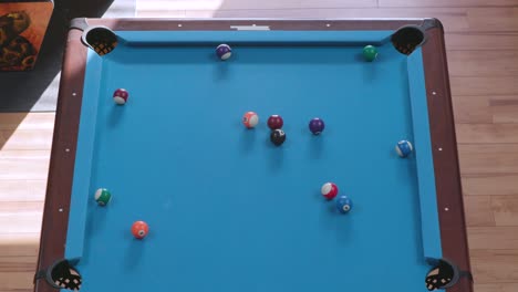 overhead view of breaking racked pool balls in eight-ball formation on blue billiards table