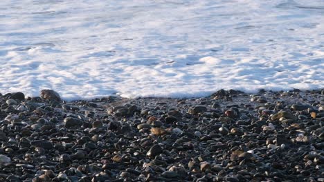 close up on beach pebbles and foaming waves