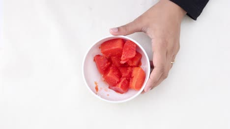 mujer comiendo cubos de papaya frescos