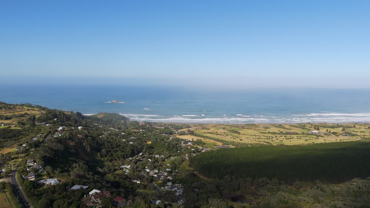 Stunning drone view of Muriwai beach and surrounding town on Auckland’s scenic west coast, popular spot for surfing, nature walks and travel adventures in New Zealand.