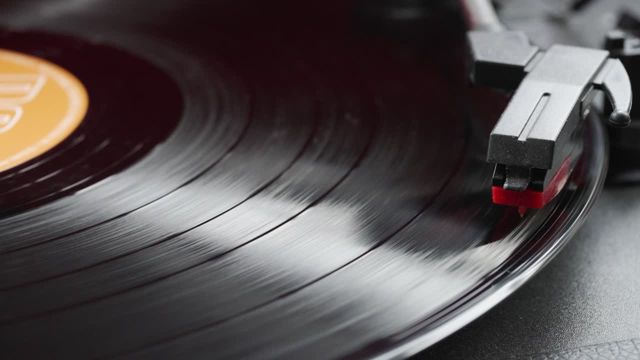 Close-up view of spinning black vinyl record and stylus on retro record player