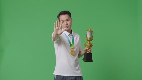 hombre sosteniendo el trofeo y mostrando el gesto de detención