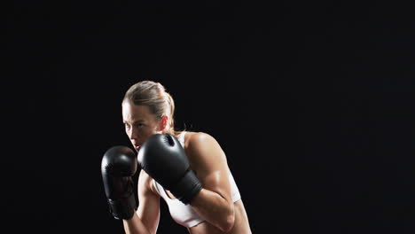 young caucasian woman boxer in boxing stance, ready to train on black background