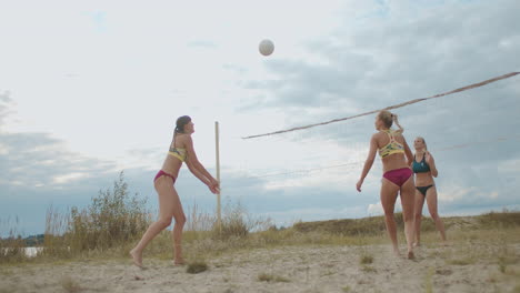 friendly match of two women beach volleyball team ladies are playing on court at summer day against cloudy sky