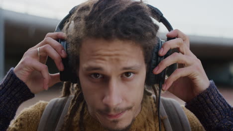 close up portrait confident young mixed race man student looking serious takes off headphones calm independent male wearing dreadlocks hairstyle slow motion