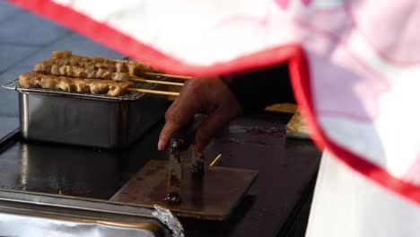 hand turning skewers over a charcoal grill