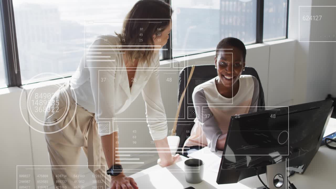 Business coworker leaning onto desk and pointing at monitor, guiding seated coworker typing report