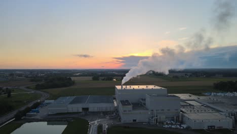 flying toward a factory with a beautiful sunset in the background