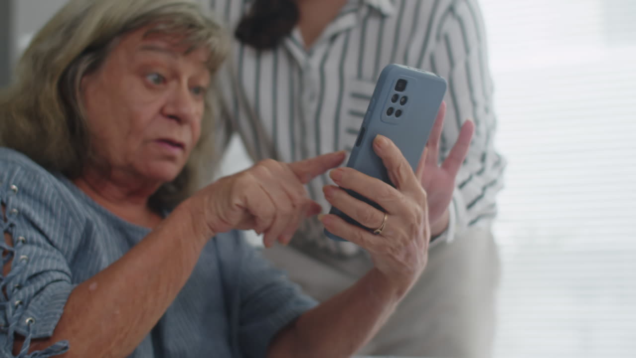 Person Showing Senior Woman How to Call on Video on Smartphone