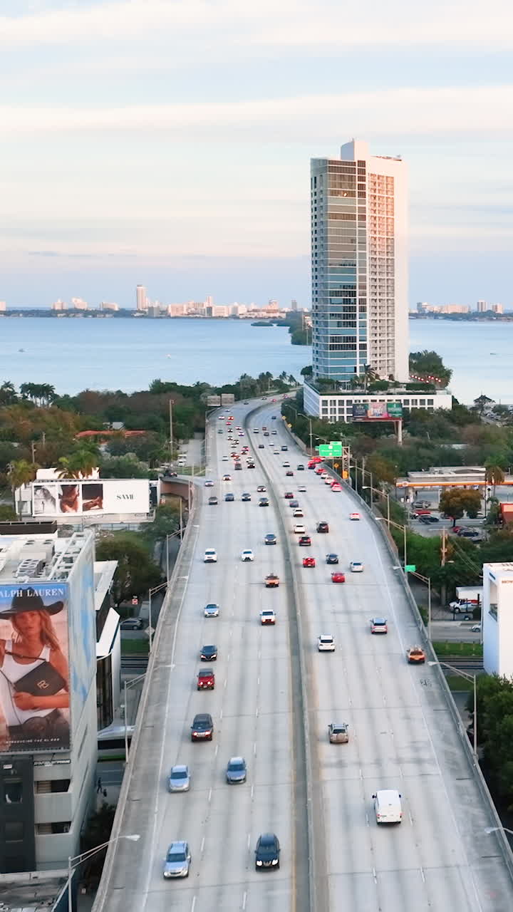 Miami, Florida, USA - January 05, 2024: Beautiful Miami skyline. Flight of the drone over the freeway with cars. Evening city with houses overlooking the bay of the Atlantic Ocean. Vertical video