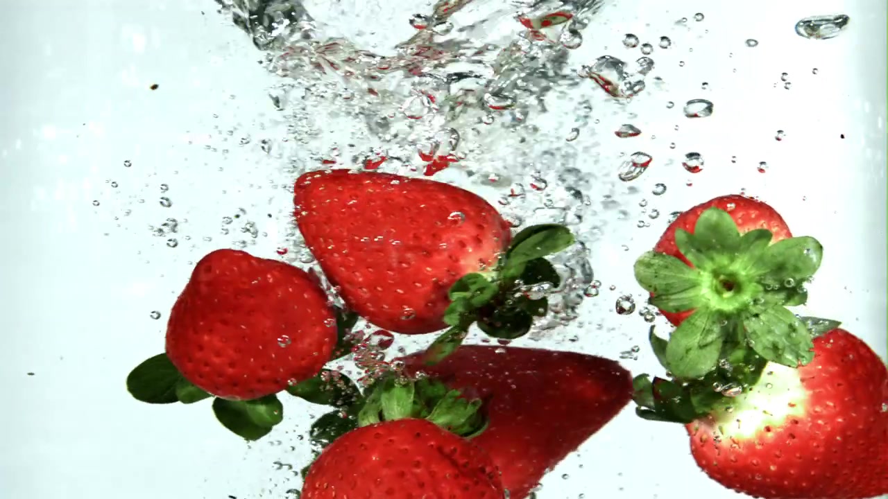 Fragole rosse fresche che schizzano in acqua limpida.