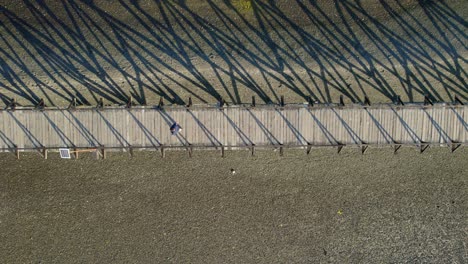 A-person-Walks-Alone-through-wooden-bridge-Above-Sand-at-Aucar-Island,-Aerial-Drone-zenithal-View,-Andean-Patagonia,-Chile