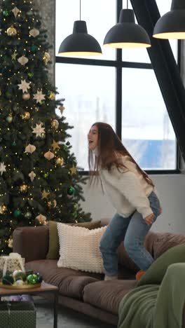 happy girl jumping on sofa during christmas celebration