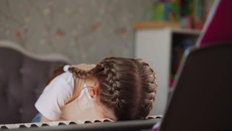 tired girl in orthopedic corset rests head on piano keyboard