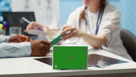 paciente y especialista médico en una visita de chequeo junto a la pantalla verde