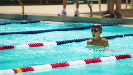 young boy dives off block in swimming competition, breaststroke - tracking shot