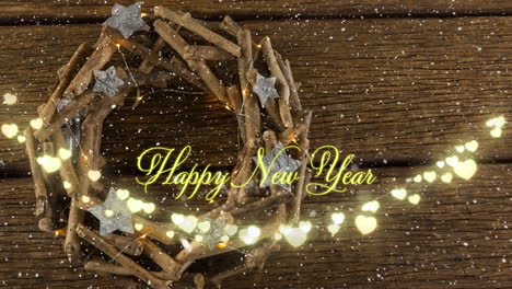 animation of happy new year text in yellow over heart string lights and christmas wreath