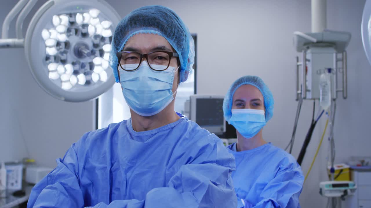 varios cirujanos masculinos y femeninos que usan máscaras faciales y ropa protectora en el quirófano