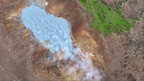 "An-aerial-drone's-fixed-view-of-Engjahver's-steam-lake-on-the-Reykjanes-Peninsula-in-Iceland,-with-steam-drifting-to-the-right