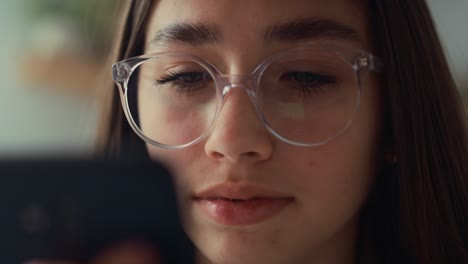 Close-up-of-caucasian-teenage-girl-browsing-phone-while-sitting-on-bed