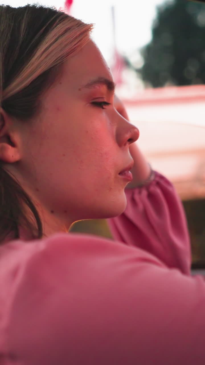 mujer sentada en su coche atrapado en el tráfico durante la noche con reflejos de luz roja suave brillando en su cara, una vista borrosa de otro vehículo se puede ver cerca con la luz borrosa del coche