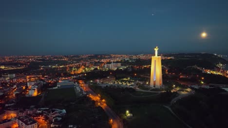 Drohnenaufnahmen-Fliegen-Vorwärts-Und-Filmen-Die-Christo-Rei-Statue-Und-Den-Mond-Vor-Sonnenaufgang