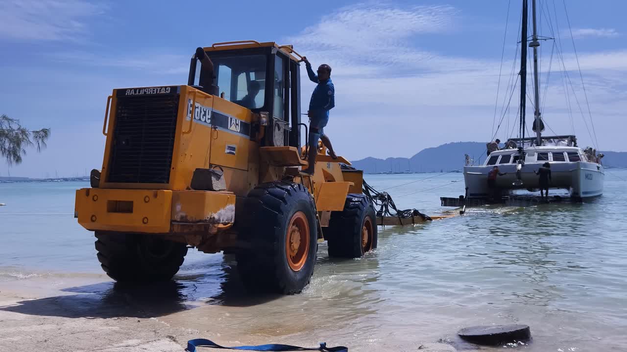 해변에 있는 무거운 용량의 발굴기가 배를 고 내립니다.