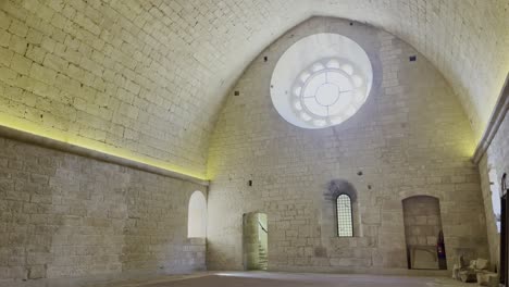 large dormitory in a monastery with high sandstone side walls a large round window, empty