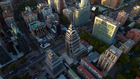 Un-Bullicioso-Paisaje-Urbano-Al-Atardecer-Con-Rascacielos-Y-Zonas-De-Parques-Urbanos,-Bañado-Por-Una-Luz-Dorada,-Vista-Aérea